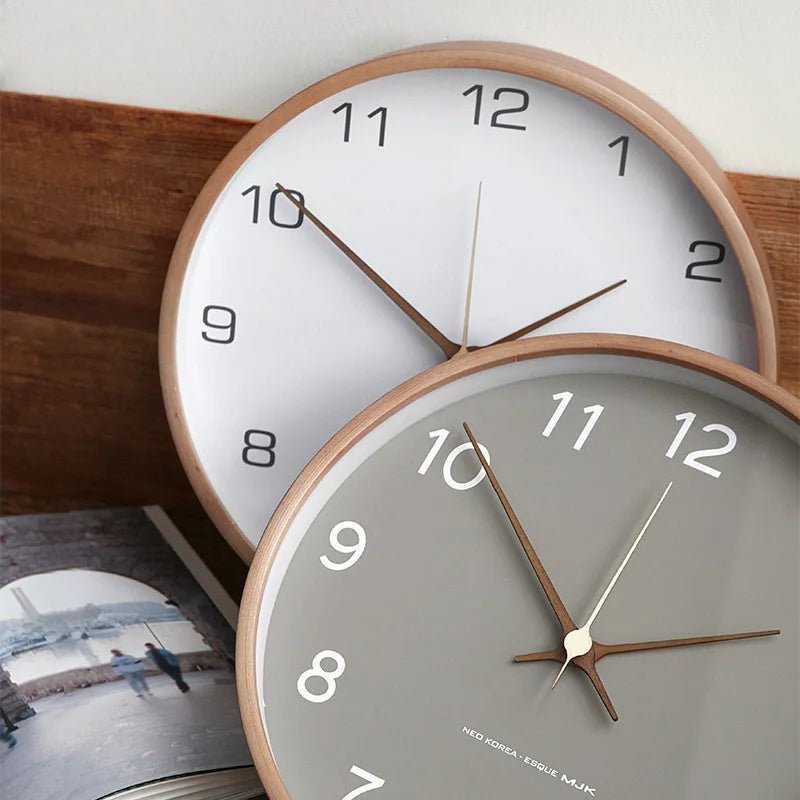 Horloge murale design Sienne de couleur taupe avec chiffres noirs, style moderne et élégant, fixée sur un mur blanc.